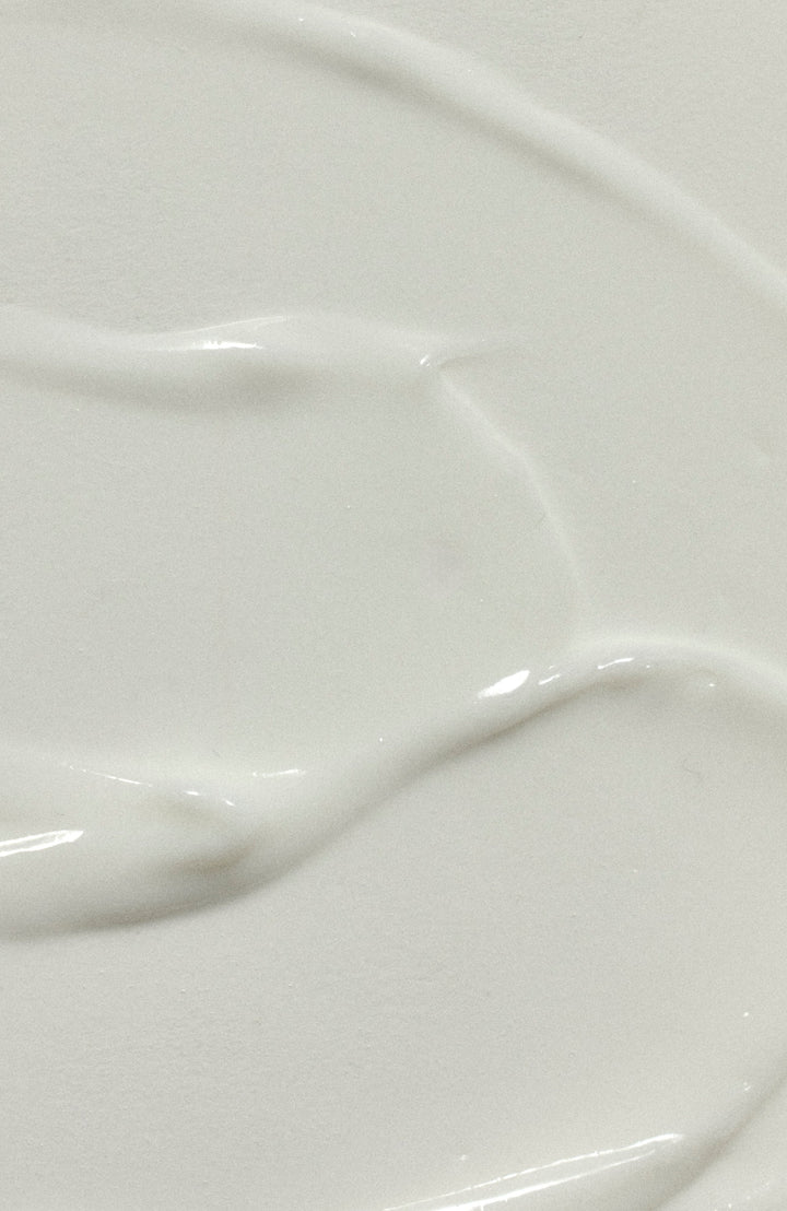 Close-up of a thin, creamy white swirl of Milk Hair Serum showing its light texture.